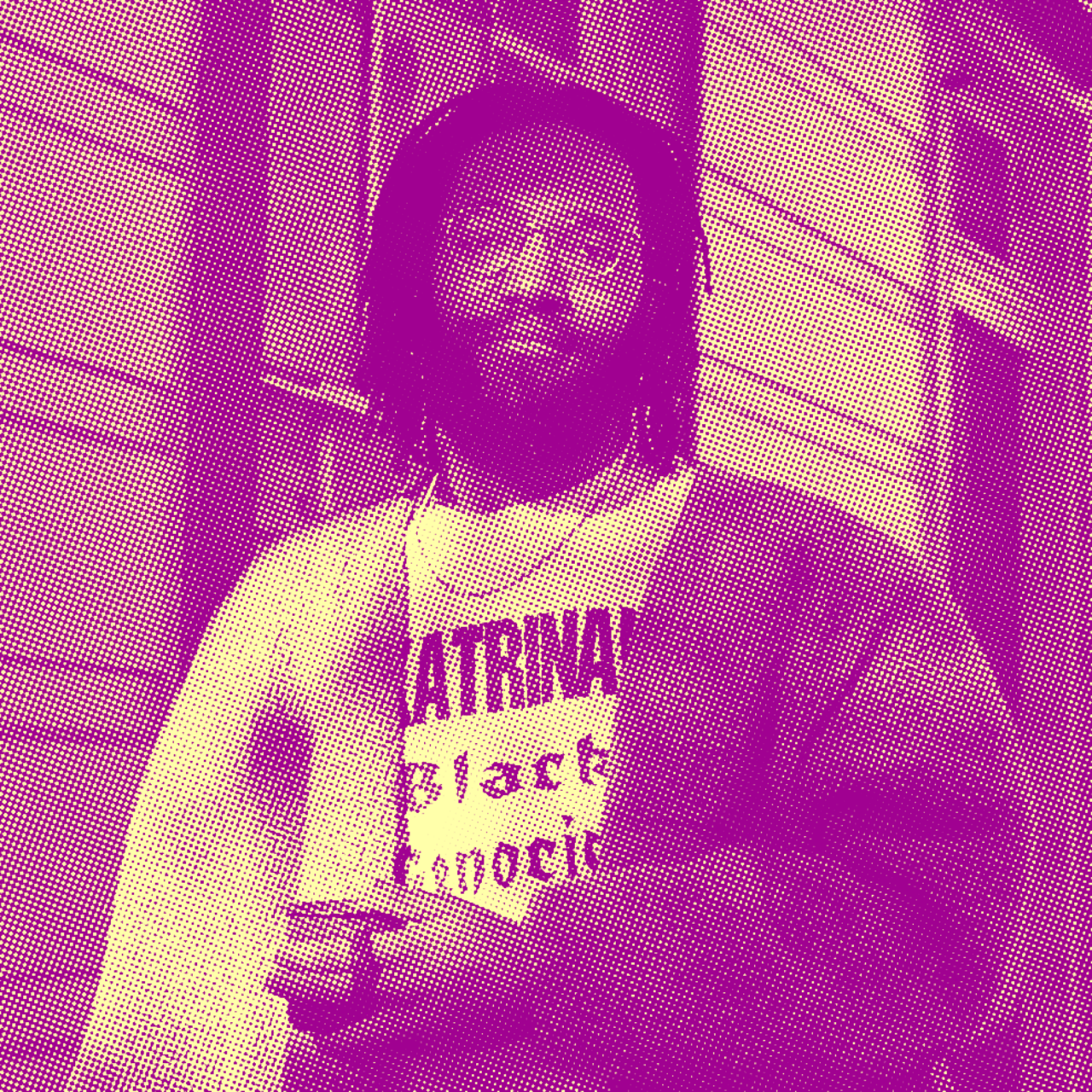 A man with brown skin, medium length dreadlocks wearing gold glasses stands behind a blue shotgun home on his balcony wearing a light brown cardigan with a t-shirt reading "Katrina! Black Genocide" as he holds a blue enamel coffee cup looking at the camera directly with a small smile apparent.