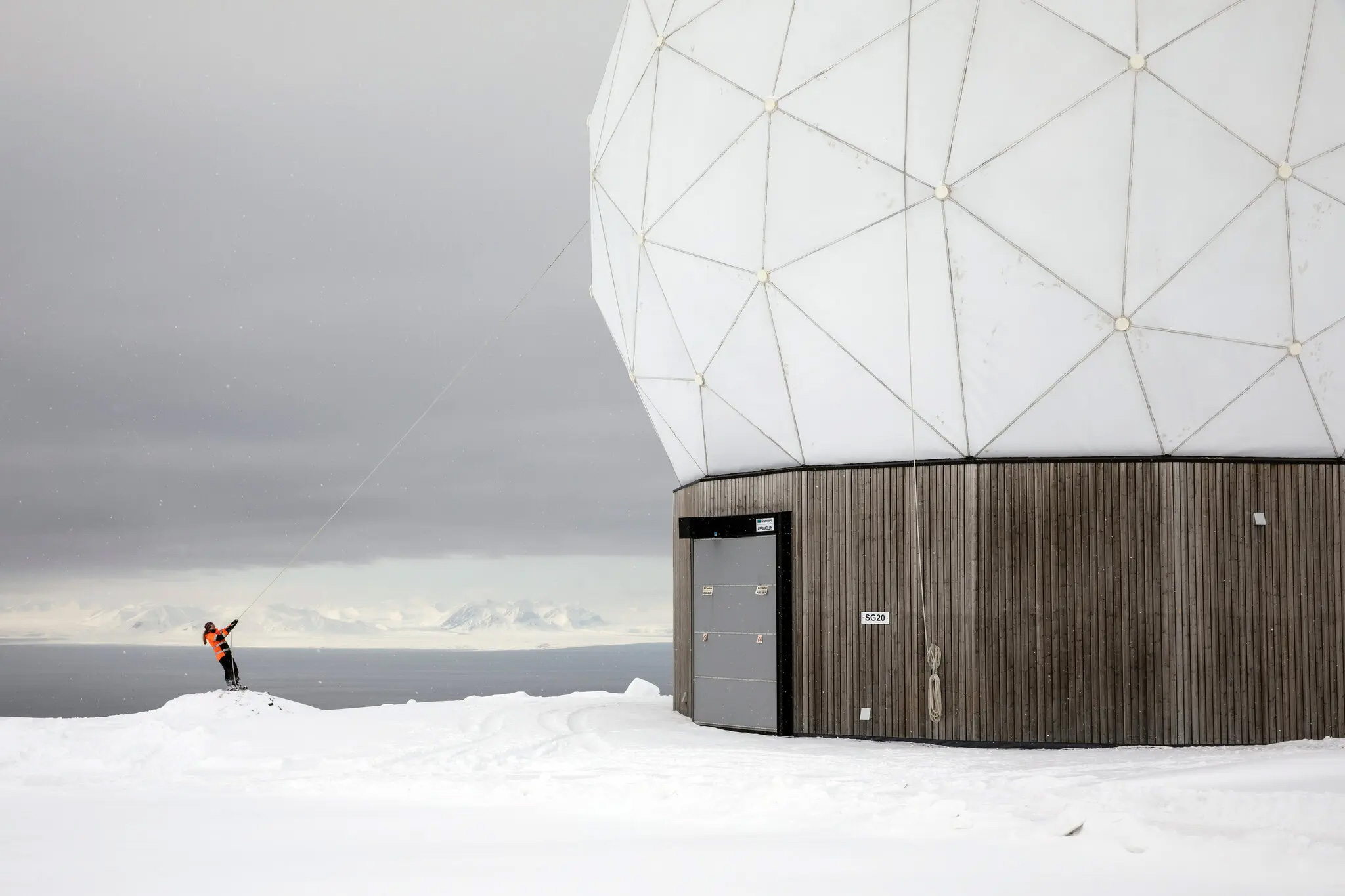 A member of the SvalSat team removed snow from an antenna dome.