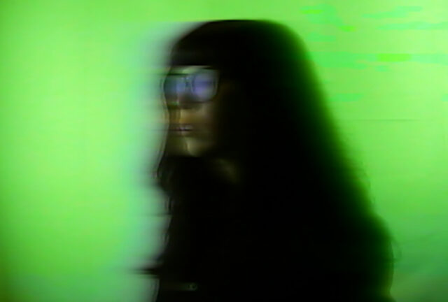 Pictured is artist Chloe Alexandra Thompson. She is a Cree person with long dark hair. A blurred image depicts a person in profile wearing glasses against a neon green background, conveying a sense of motion and digital distortion.